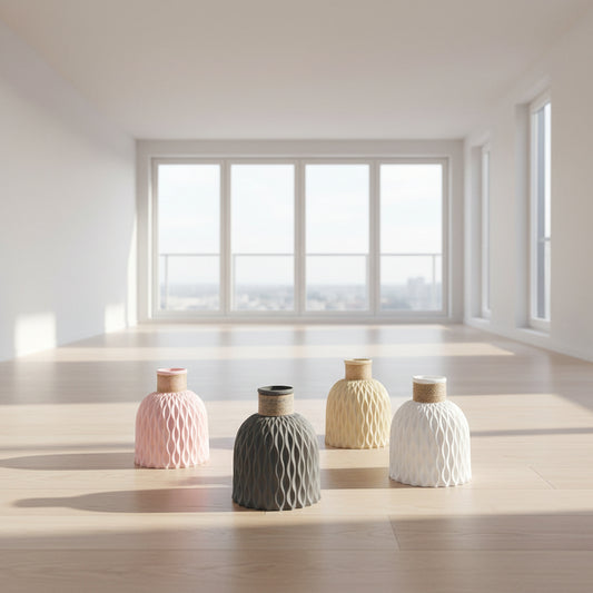 Four textured vases in pink, beige, gray, and white on a light surface with a neutral background.